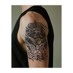 Un leone incoronato appare sereno sopra un angelo alato in preghiera. Questo tatuaggio realistico evoca forza e pace, circondato da nuvole, esprimendo coraggio e fede.
