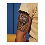 Una croce con i volti di Gesù con una corona di spine, un leone ruggente e un angelo in preghiera a terra. Il disegno simboleggia fede, forza e protezione divina, combinando spiritualità e coraggio.