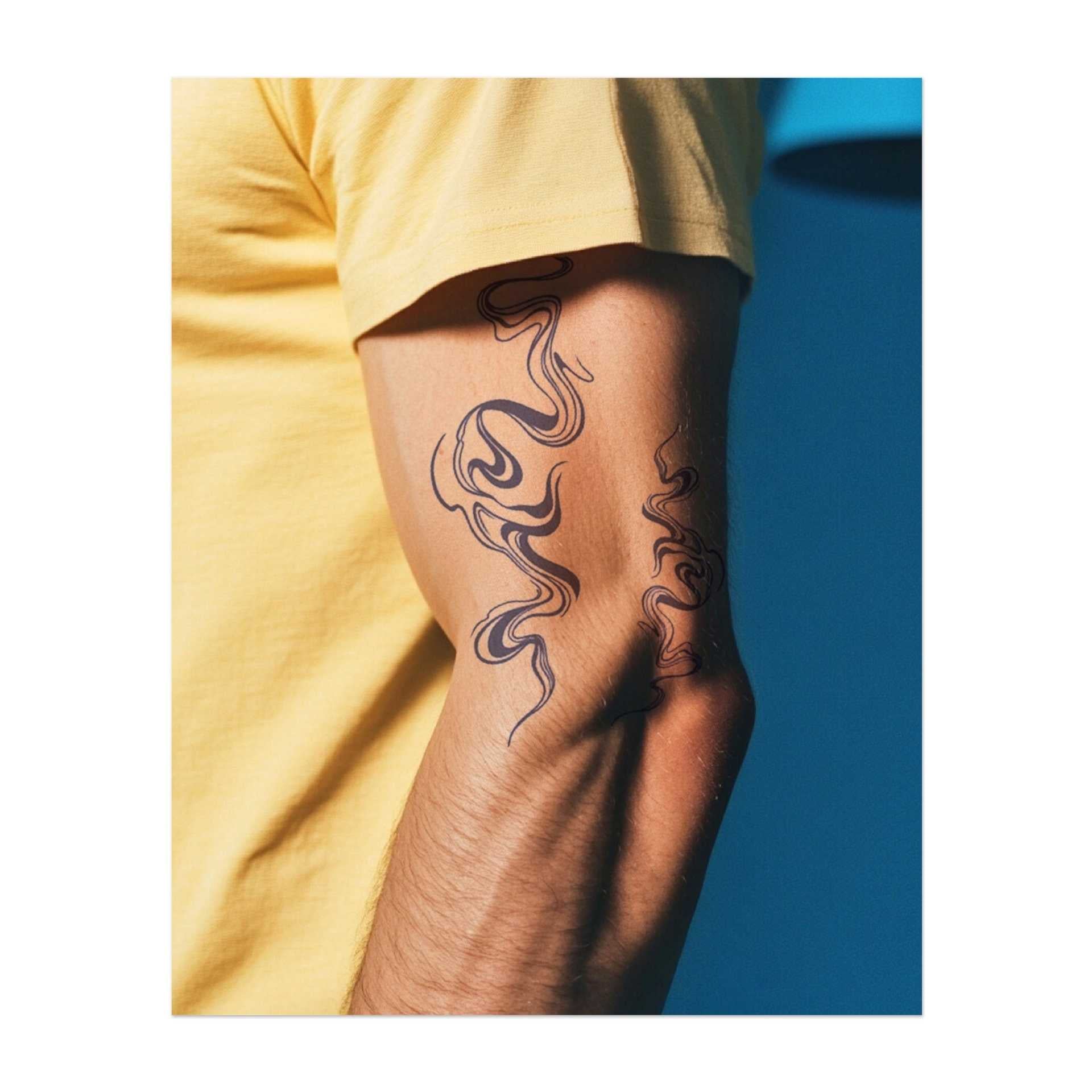 Linee curve e sinuose che ricordano il fumo o un liquido che scorre, che si muovono in un motivo aggraziato e organico. Il tatuaggio simboleggia fluidità, cambiamento e libertà.