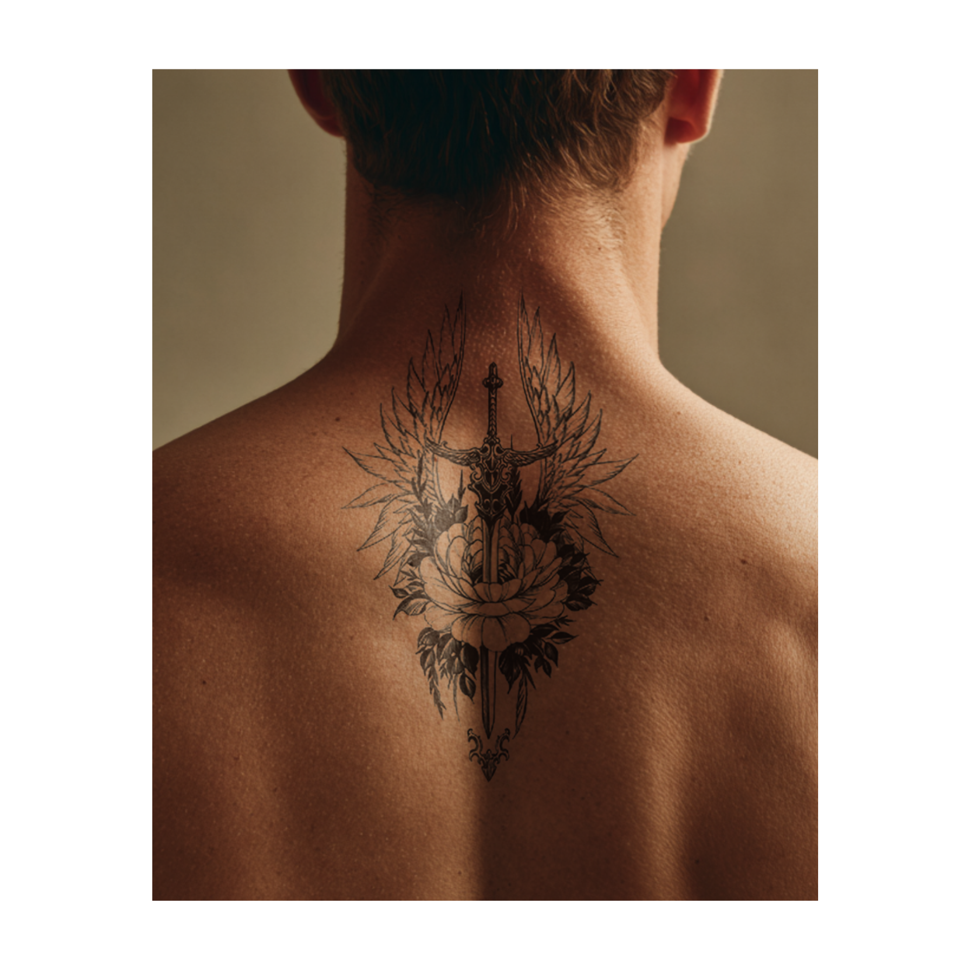 Una spada dettagliata con ali d'angelo si erge dietro un fiore in fiore. Questo tatuaggio realistico unisce forza e bellezza, ricordandoti di proteggere ciò che è puro e buono.