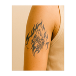 Un terrificante volto di lupo circondato da fiamme vorticose. Il lupo alza lo sguardo, ulula e la sua pelliccia si scioglie nel fuoco. Il tatuaggio è disegnato in un audace stile tribale e raffigura forza, fuoco ed energia selvaggia.