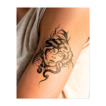 Una figura inquietante, simile a una Medusa, con il volto di pietra, la pelle screpolata e gli occhi senza vita, è coronata da serpenti contorti, che simboleggiano pericolo, potere e misticismo in un audace stile blackwork.