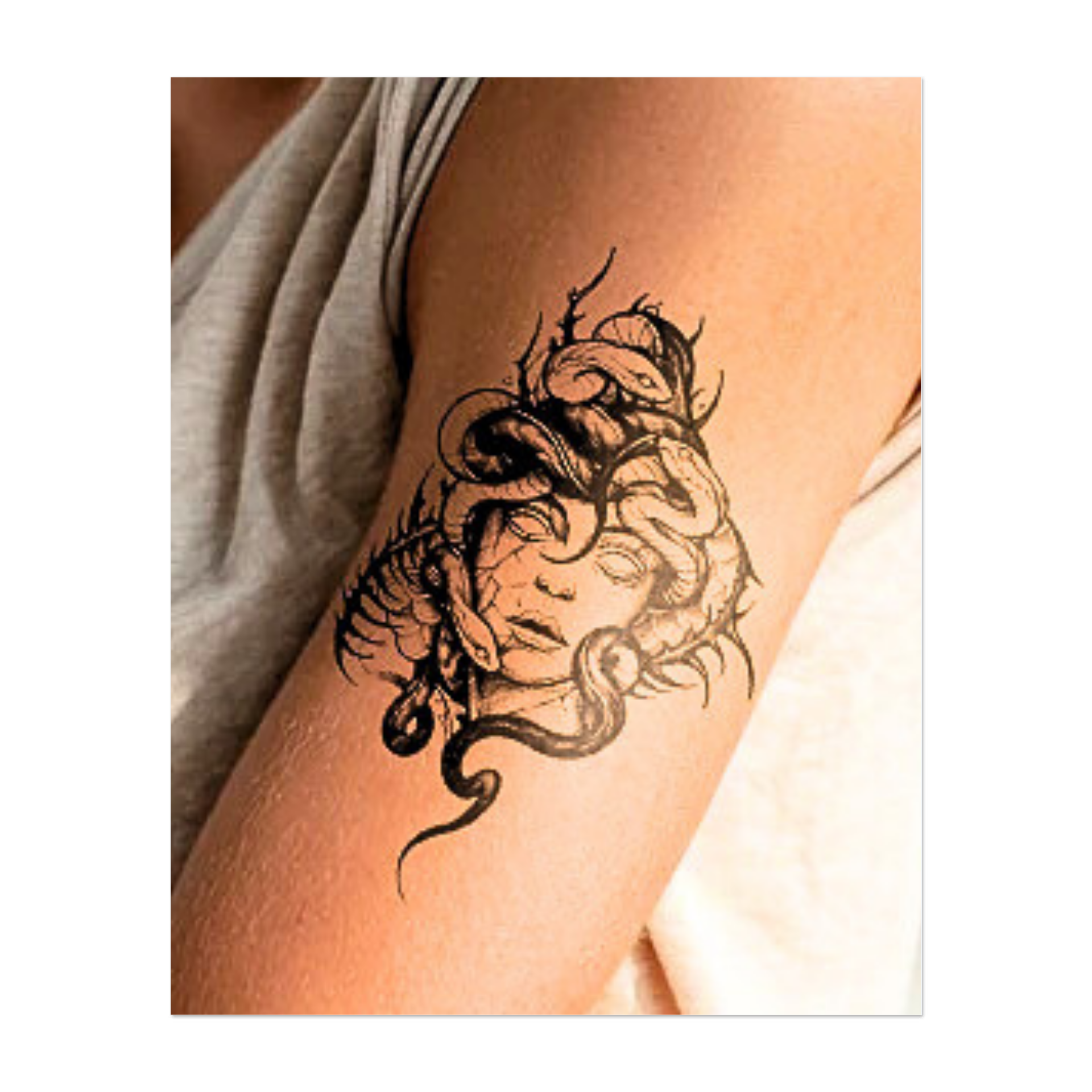 Una figura inquietante, simile a una Medusa, con il volto di pietra, la pelle screpolata e gli occhi senza vita, è coronata da serpenti contorti, che simboleggiano pericolo, potere e misticismo in un audace stile blackwork.