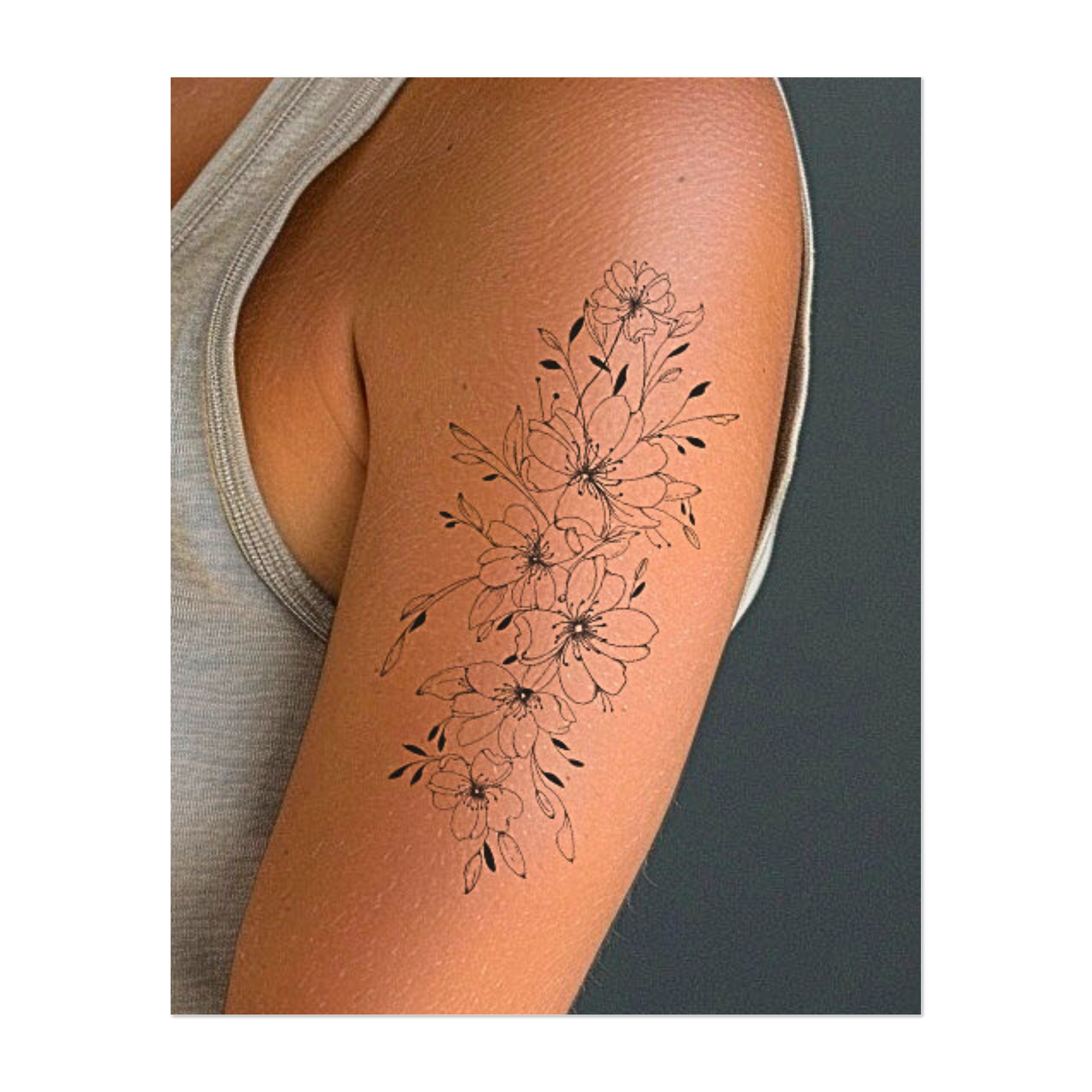 Un elegante tatuaggio raffigurante fiori di ciliegio disegnati in modo intricato che formano delicatamente un tralcio verticale. Le linee delicate, i boccioli delicati e le foglie armoniosamente disposte conferiscono al disegno una bellezza poetica e senza tempo.
