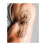 Una figura serena, vestita con una tunica, irradia energia divina sotto un alone radioso, con le mani aperte in un gesto di pace. Linee decise e curve delicate creano una presenza potente e spirituale ed evocano purezza e protezione.