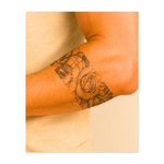 Un bellissimo tatuaggio a forma di nastro con un mix di rose in fiore e fiori delicati intrecciati con foglie rigogliose. Questo tatuaggio simboleggia la bellezza, la crescita e l'armonia della natura.