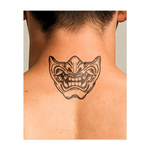Questo sorprendente tatuaggio raffigura una maschera demoniaca stilizzata con tratti esagerati e un ampio sorriso sdentato. Ispirato ai tradizionali disegni oni giapponesi, rappresenta caos, protezione e pura emozione: un mix di minaccia e misticismo in un sorprendente design scolpito.
