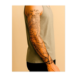 Un angelo con un bastone si libra tra raggi radiosi e nuvole ondeggianti, incoronato da un cielo stellato. In basso, mani giunte in preghiera e una colomba in volo simboleggiano pace e devozione. Questo tatuaggio incarna la grandezza spirituale e la serenità divina in uno stile classico e riverente.