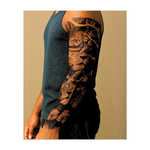 Una potente sequenza di volti di leone conduce a un guardiano dagli occhi luminosi sotto un orologio rotto, simbolo di coraggio nel tempo. Con una croce e una figura di Cristo in preghiera al centro, questo tatuaggio unisce fede spirituale, forza interiore ed eterna vigilanza.