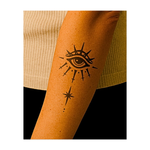 Questo tatuaggio simbolico raffigura un occhio onniveggente circondato da punte radiose e delicate forme a forma di pugnale che scorrono sotto. Una stella celeste ancora il disegno sottostante, rappresentando chiarezza attraverso il dolore, protezione e illuminazione attraverso il sacrificio.