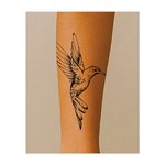Questo tatuaggio temporaneo raffigura un colibrì delicatamente disegnato in volo. Con le sue linee dettagliate, la postura dinamica e le ali elegantemente spiegate, questo disegno incarna la leggerezza, la grazia e la bellezza della natura.