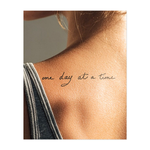 Elegante scritta a mano con il messaggio motivazionale "Un giorno alla volta". Le linee morbide evocano calma e sicurezza, perfette per un promemoria quotidiano di consapevolezza e serenità.