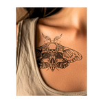 Questo tatuaggio scuro ed elegante raffigura una falena con ali dettagliate e motivi a forma di teschio nascosti intrecciati sul corpo. Un teschio centrale incorona il disegno, simboleggiando la trasformazione, la mortalità e la bellezza inquietante che aleggia tra la vita e la morte.