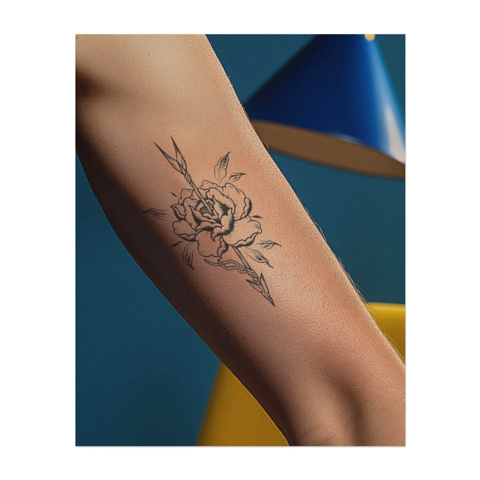 Una splendida rosa trafitta da una freccia affilata, con petali e foglie intrecciati attorno ad essa. Questo tatuaggio è realizzato in uno stile delicato, che gli conferisce un aspetto morbido, quasi vintage. È un mix di eleganza e forza, perfetto per chi ama la natura e il coraggio.