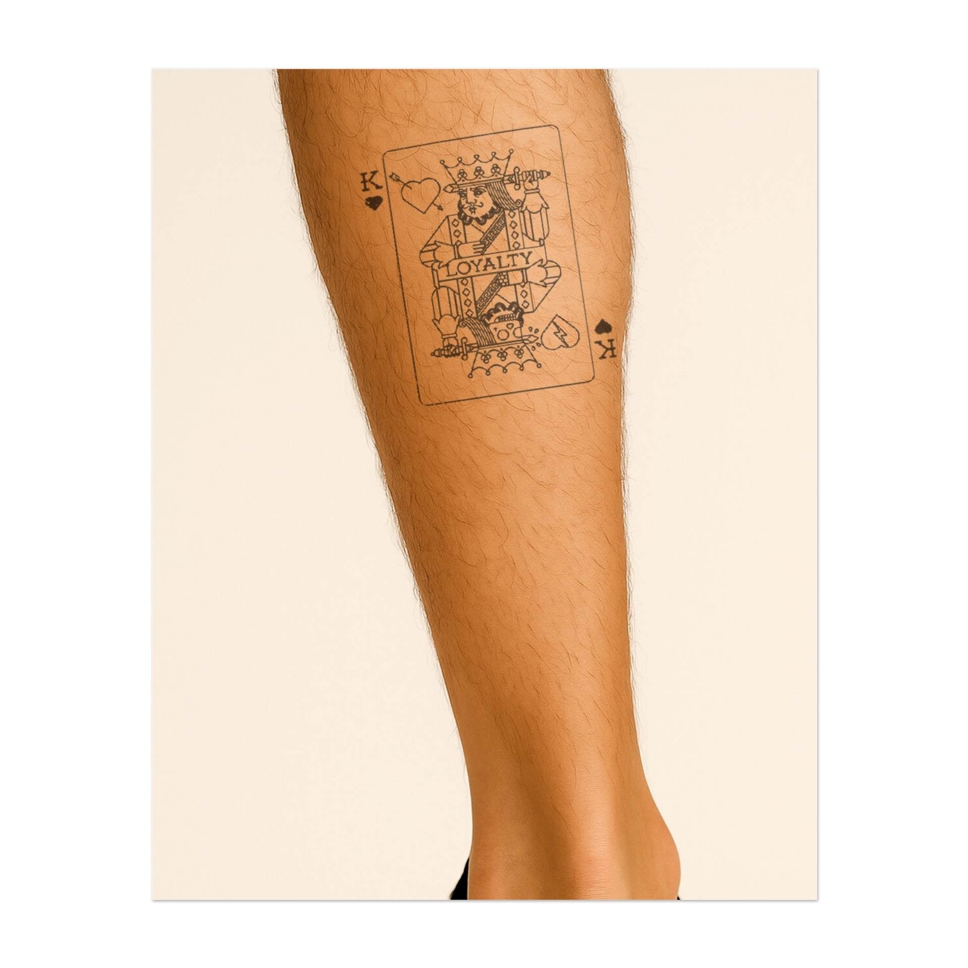 Una carta da gioco raffigurante un Re di Cuori con la scritta "LEALTÀ" sul petto. Il tatuaggio raffigura una figura regale con una spada, simbolo di forza e devozione. Rappresenta lealtà e onore, perfetto per chi apprezza queste qualità.