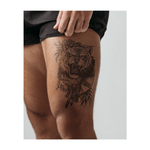 Una tigre ruggente con una rosa e delle foglie accanto a un orologio rotto. Questo tatuaggio realistico incarna forza, coraggio e audacia, ricordandoti che il tempo non può contenere la tua passione.