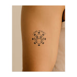 Un virus dei cartoni animati con una mascherina e la scritta "VENGO IN PACE". Questo tatuaggio porta umorismo in questi tempi e simboleggia la resilienza e le buone vibrazioni nei momenti difficili.