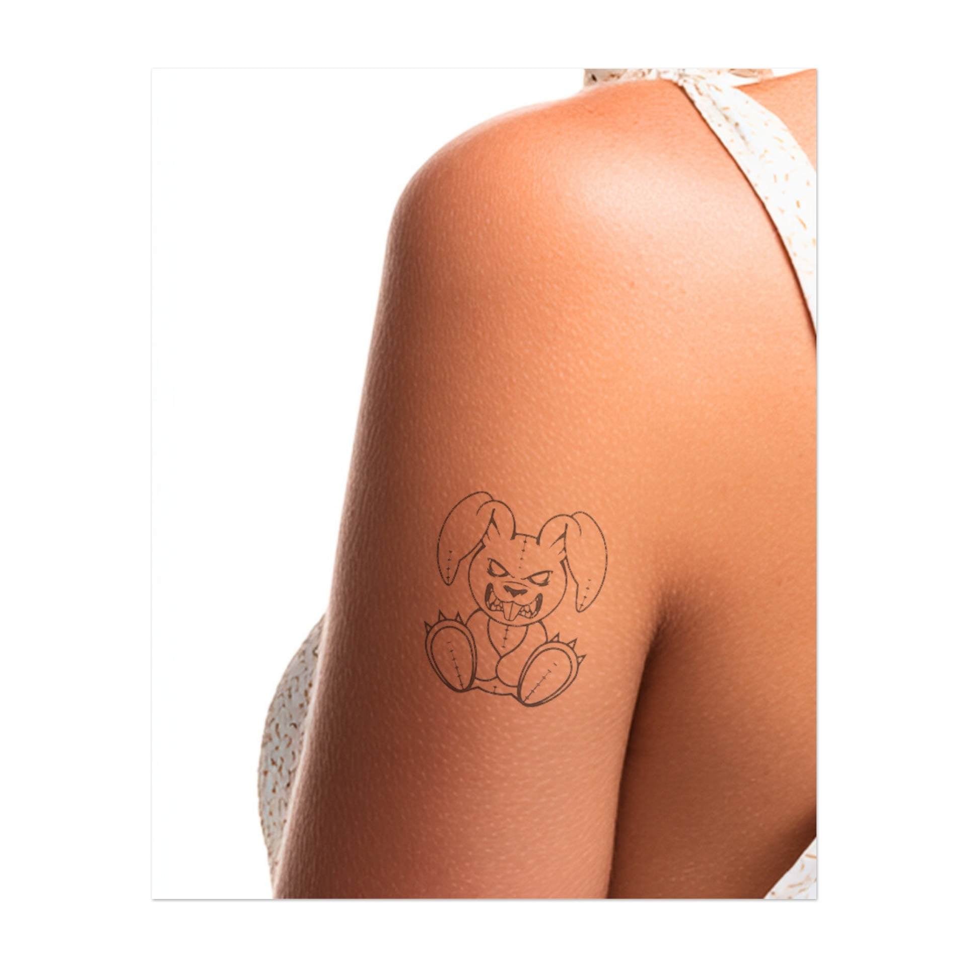 Un coniglietto dispettoso con un'espressione ringhiante e denti aguzzi. Questo tatuaggio rappresenta ribellione, carattere e un tocco di giocosità, perfetto per chi abbraccia la propria personalità coraggiosa e audace.