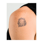 Una temibile testa di leone con un'espressione ruggente che esprime potere e autorità. Questo tatuaggio simboleggia forza, coraggio e leadership, perfetto per chi abbraccia la propria natura audace e impavida e guida con sicurezza.