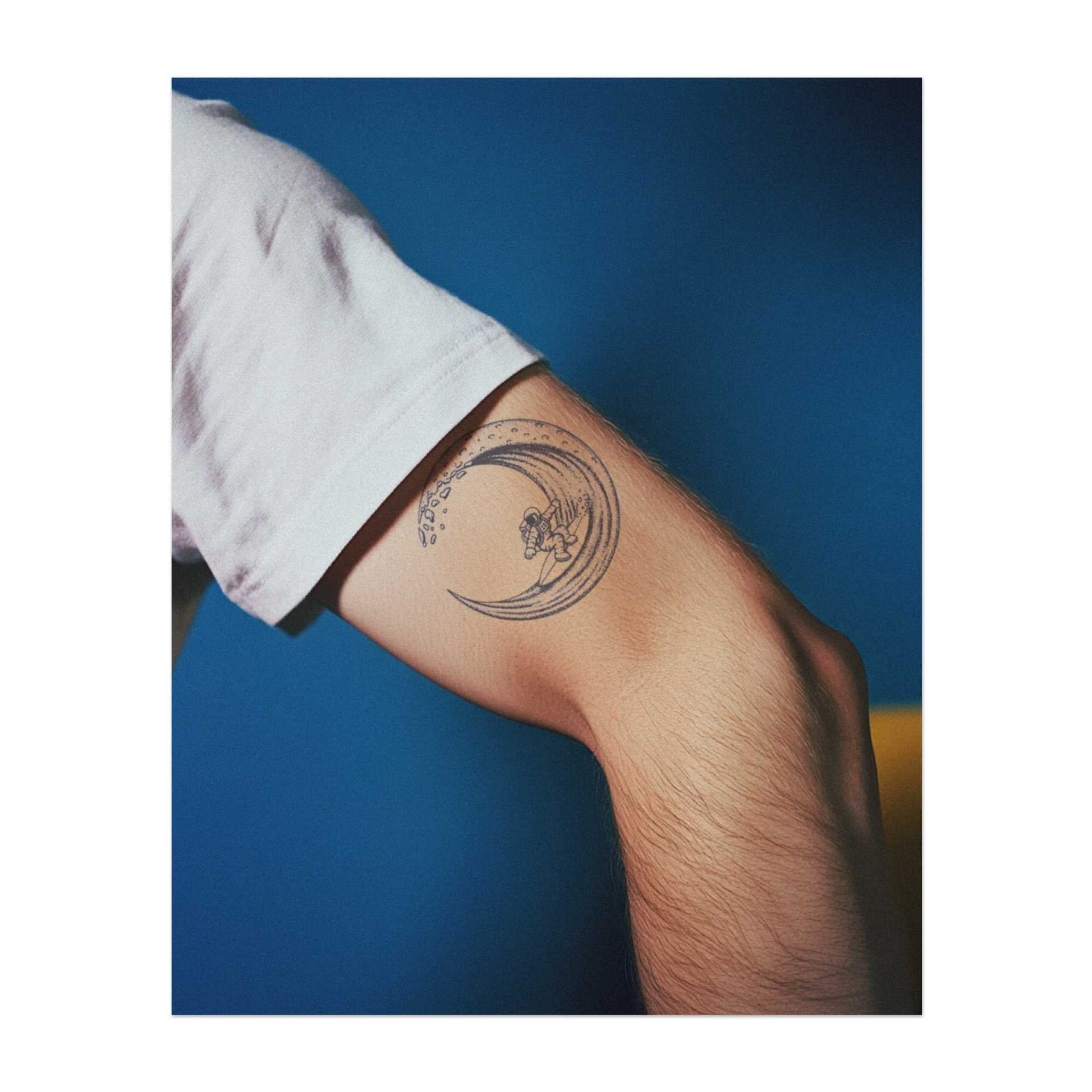 Un surfista (astronauta) che cavalca un'onda gigante, combinando l'energia dell'oceano con l'emozione della corsa. Questo tatuaggio simboleggia l'avventura, la libertà e l'abbraccio del flusso della vita, perfetto per chi vive la vita alla ricerca dell'eccitazione e della bellezza della natura.