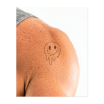 Una faccina sorridente, in stile cartone animato, che si scioglie in un sorriso. Rappresenta un'espressione distorta o surreale di felicità. Un design semplice ma d'impatto, con un tocco di stravaganza.