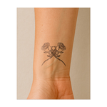 Due rose con spine intrecciate. Simboleggiano bellezza e dolore, amore con ostacoli, o un classico simbolo di romanticismo con un tocco oscuro.