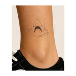 Testa di squalo con bocca aperta e denti visibili. Simboleggia potenza, aggressività o un legame con il predatore più temibile dell'oceano.