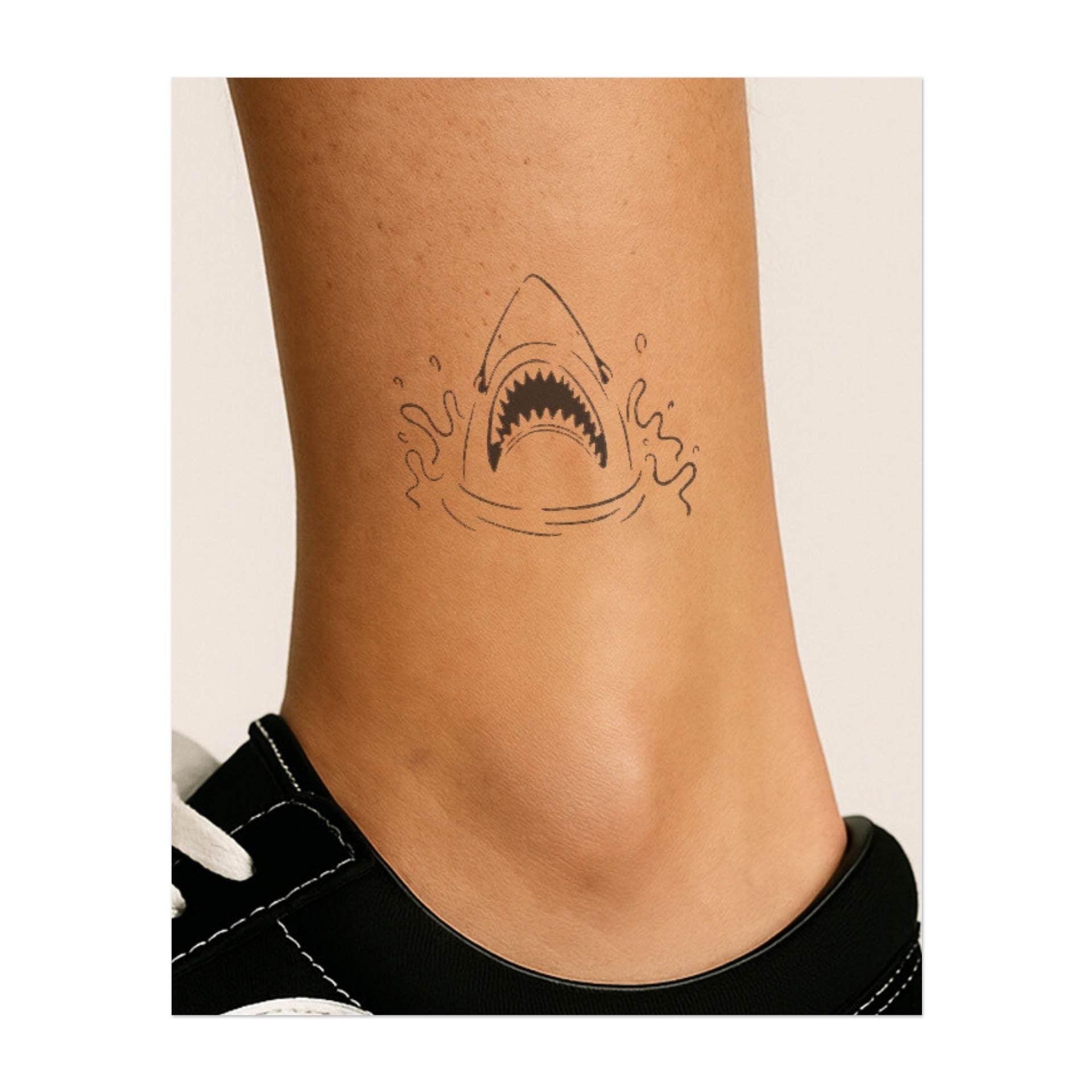 Testa di squalo con bocca aperta e denti visibili. Simboleggia potenza, aggressività o un legame con il predatore più temibile dell'oceano.