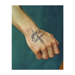 La parola "Angelo" in caratteri gotici, incastonata in una croce decorativa. Rappresenta la fede, una visione più oscura o audace della spiritualità, o un legame personale con la parola "Angelo".