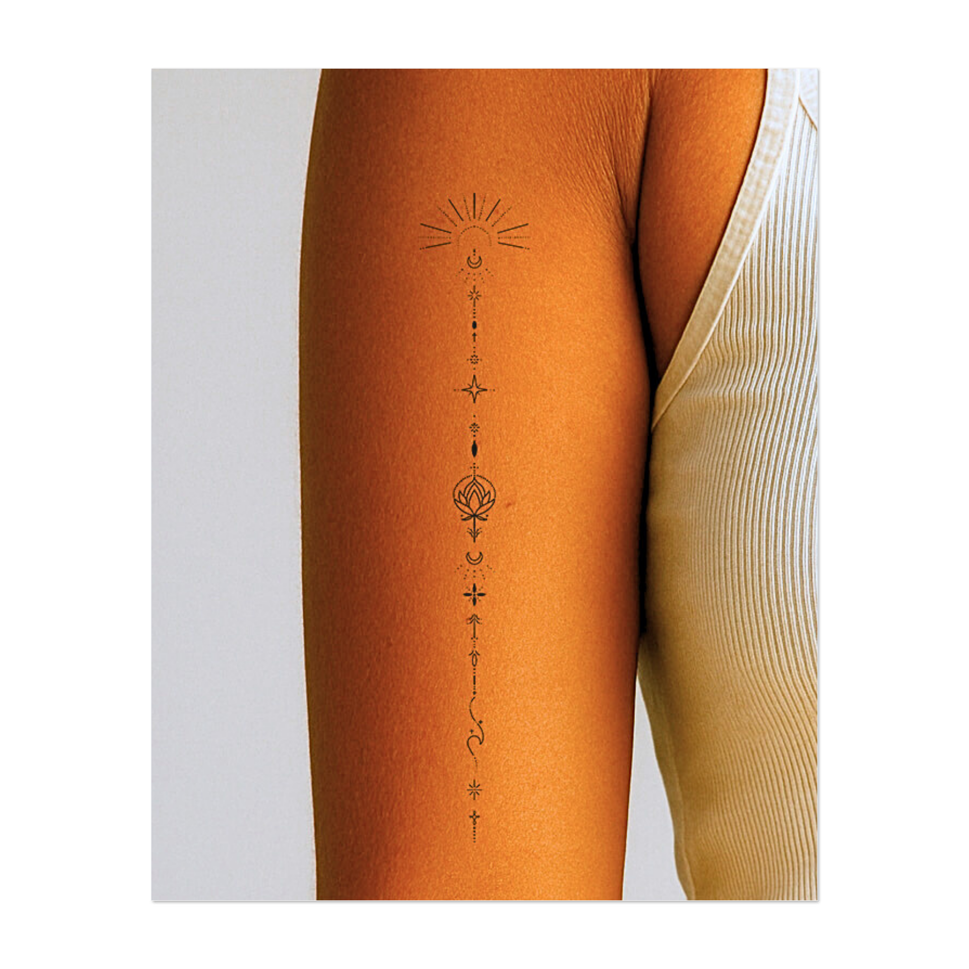 Un delicato disegno allineato verticalmente raffigurante il sole, la luna, le stelle, i fiori di loto e delicati ornamenti. Questo tatuaggio combina simboli cosmici e spirituali per formare un insieme armonioso, ideale per l'equilibrio interiore, la consapevolezza e il flusso di energia.